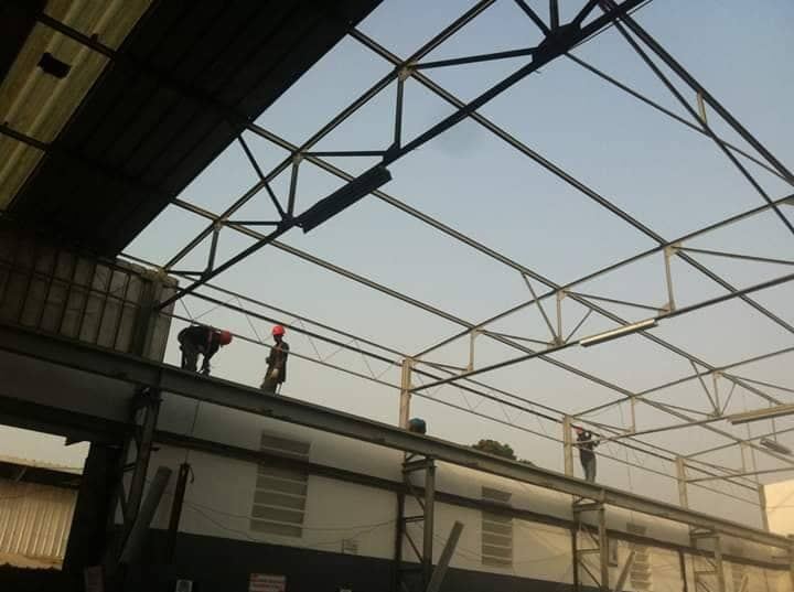 Ouvriers sur les fermes métalliques de toiture d'un bâtiment industriel