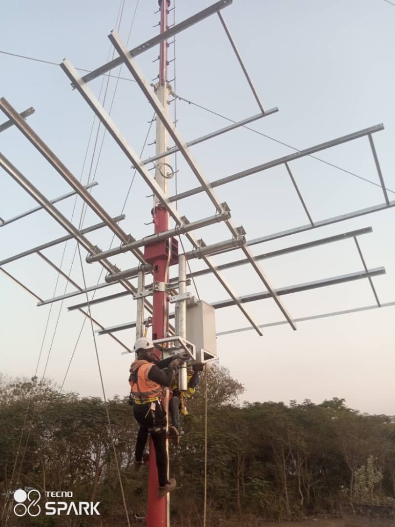 Technicien en cordiste installant un équipement radio en haut d'un pylône